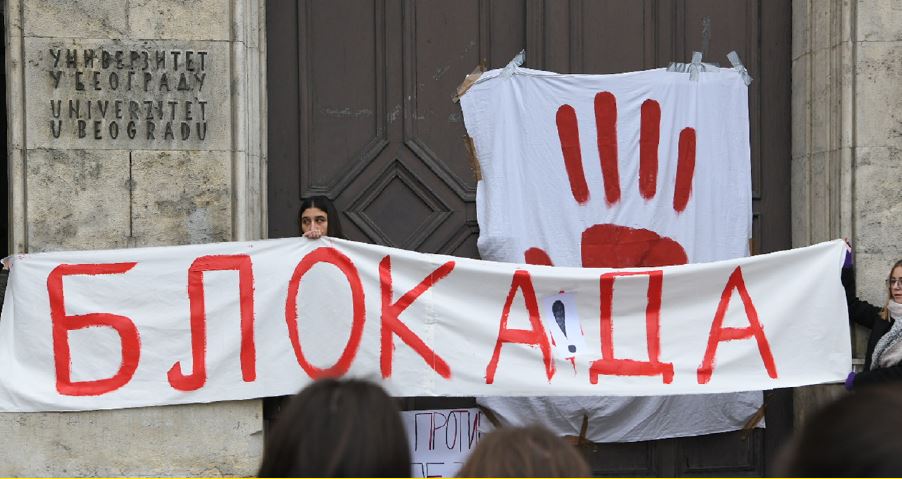 Studentin hält ein Banner mit kyrilischer Schrift "Blokada"